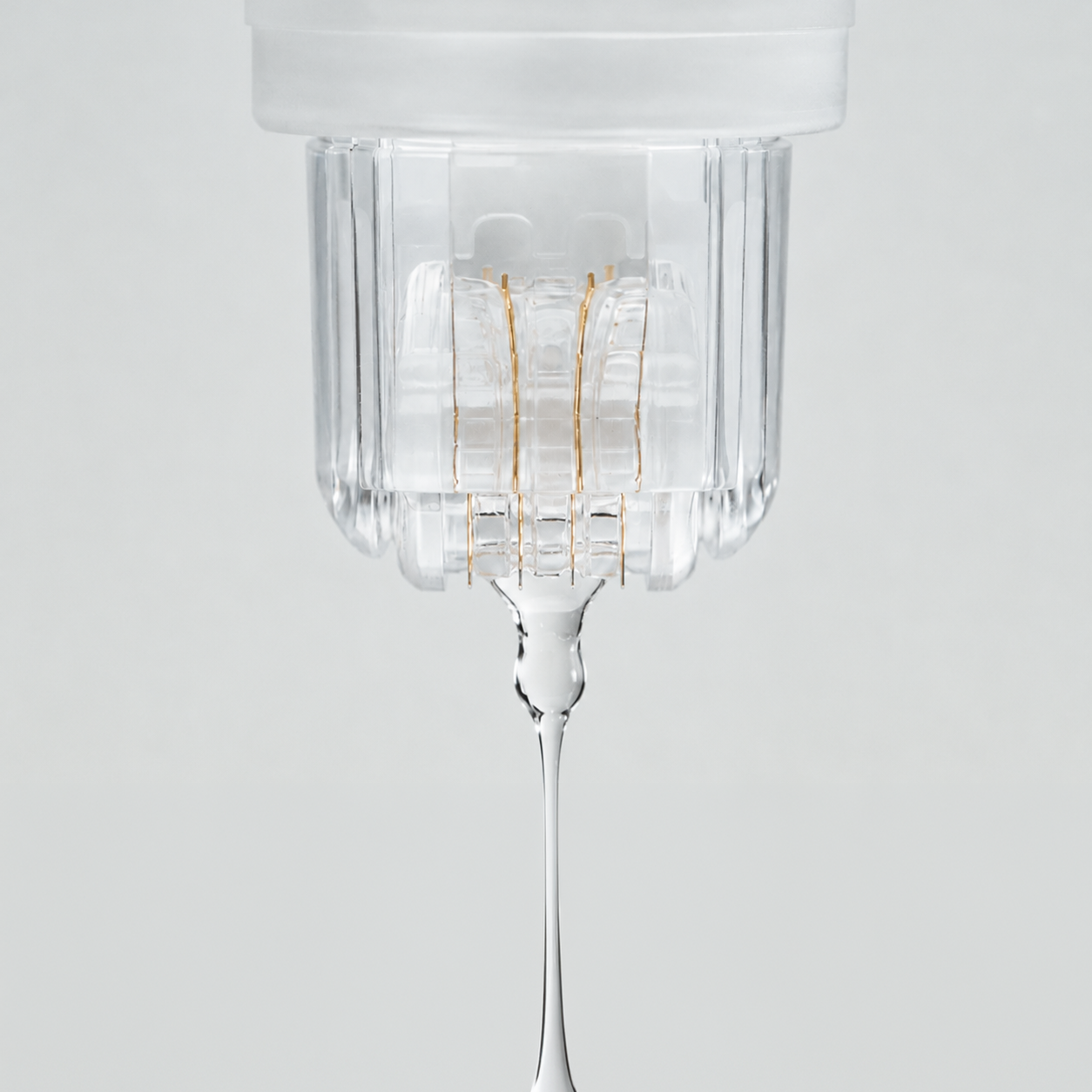 Close-up of the Roller Gold device dispensing a clear serum through its gold-plated micro-needle roller head