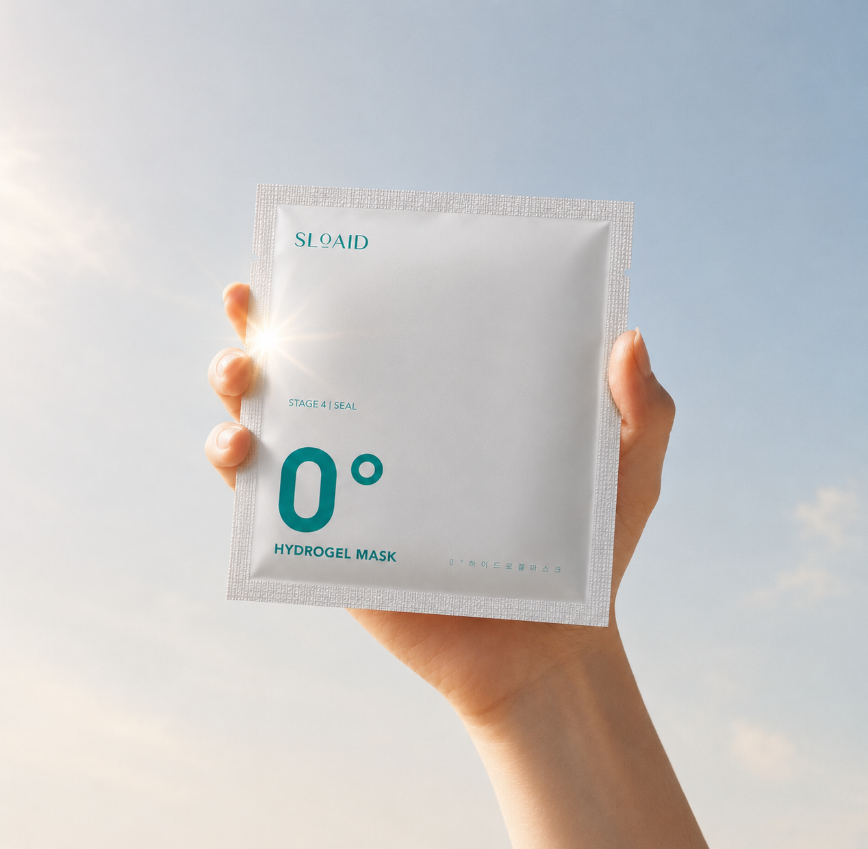 Hand holding the SLOAID 0° Hydrogel Mask against a bright sky